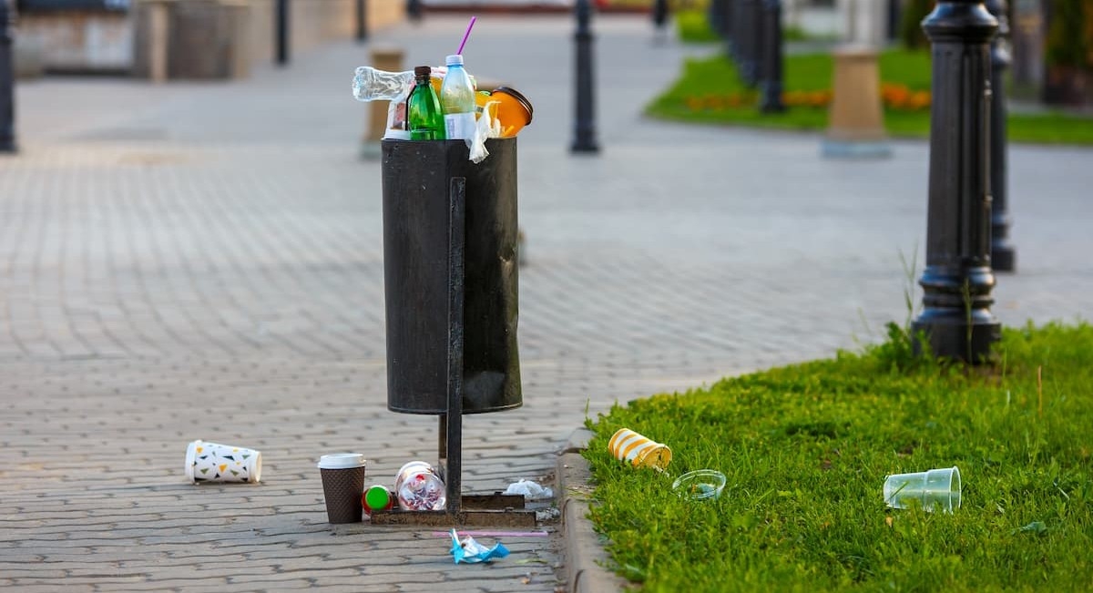 dÃ©chets abandonnÃ©s autour d'une poubelle urbaine illustrant la pollution liÃ©e aux emballages jetÃ©s dans la rue